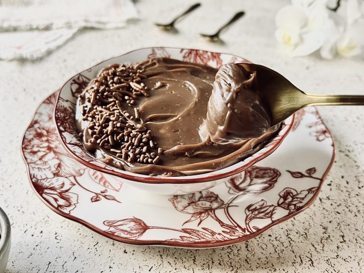 Brigadeiro pronto na tigela de servir, uma colher de brigadeiro sendo tirada.