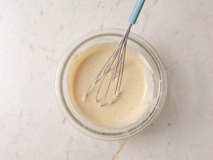 água, Whey Protein e leite em pó misturados em uma tigela de vidro.