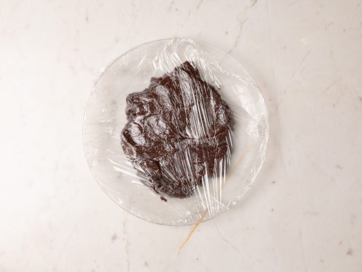 Brigadeiro transferido para um prato coberto com plástico-filme.
