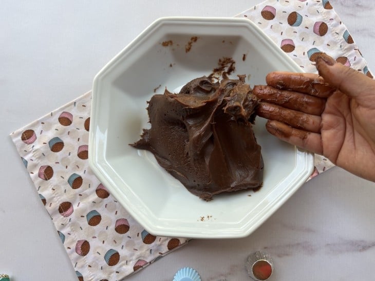 Massa do brigadeiro e no prato, mão suja de brigadeiro.