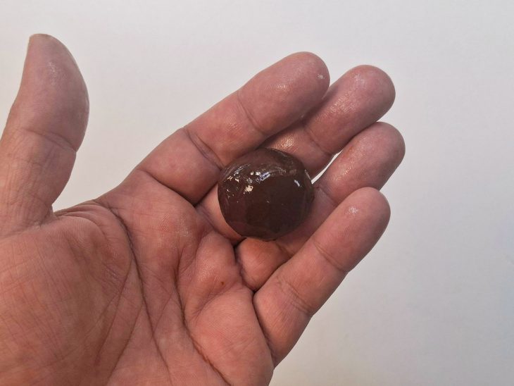 Brigadeiro descansado sendo modelado com as mãos untadas.
