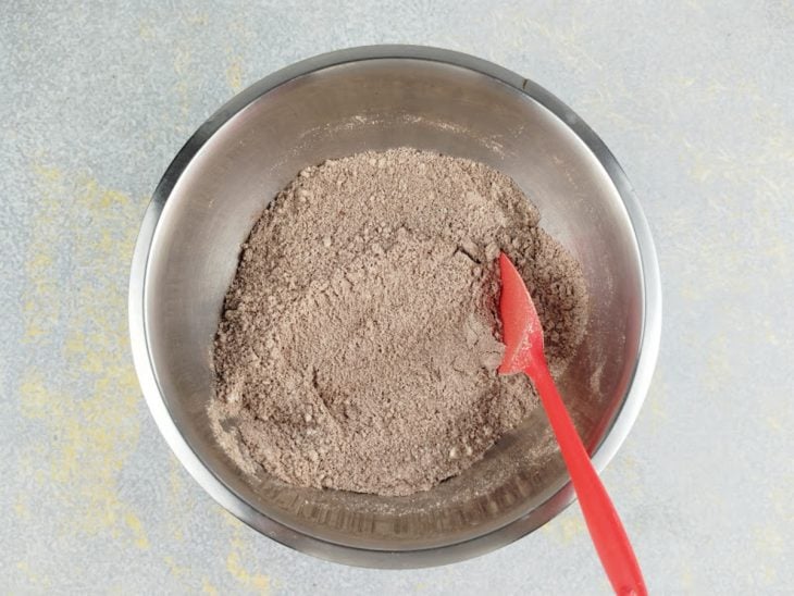Ingredientes secos sendo misturados em uma tigela até ficarem homogêneos.