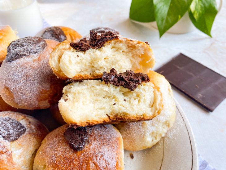 Brioches prontos para consumo, com um cortado ao meio mostrando a maciez da massa.