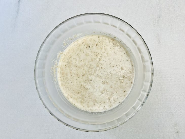 Numa tigela, o leite, o fermento e o trigo.