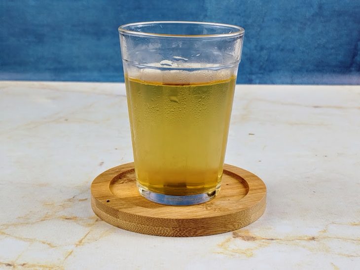 Sachê de chá infusionando em um copo de vidro com água gelada.