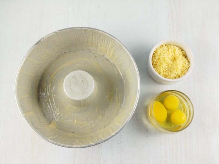 Forma untada, ovos quebrados e queijo parmesão ralado.