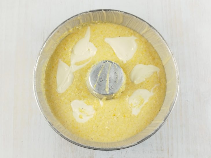 Mistura despejada na forma e requeijão colocado.