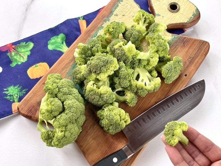 Uma tábua com brócolis sendo crotado.