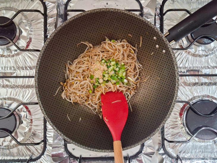 Cebolinha e gergelim sendo incorporados ao final do preparo.