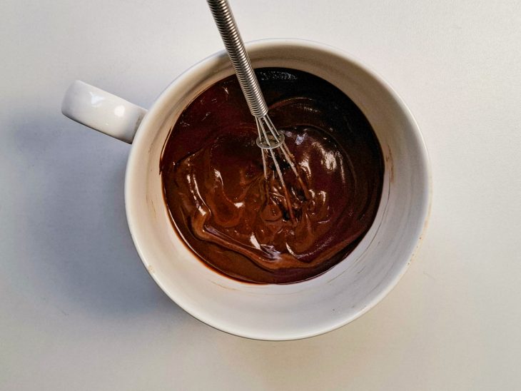 Chocolate em pó e leite incorporados na caneca.