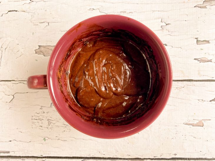 Chocolate em pó e manteiga derretida adicionados a caneca.