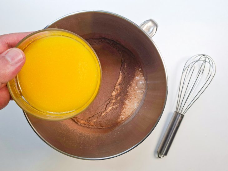 Manteiga derretida e chocolate em pó sendo adicionados à mistura.