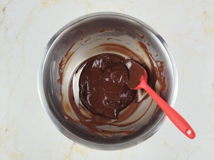 Chocolate picado e manteiga sendo derretidos juntos em uma tigela.
