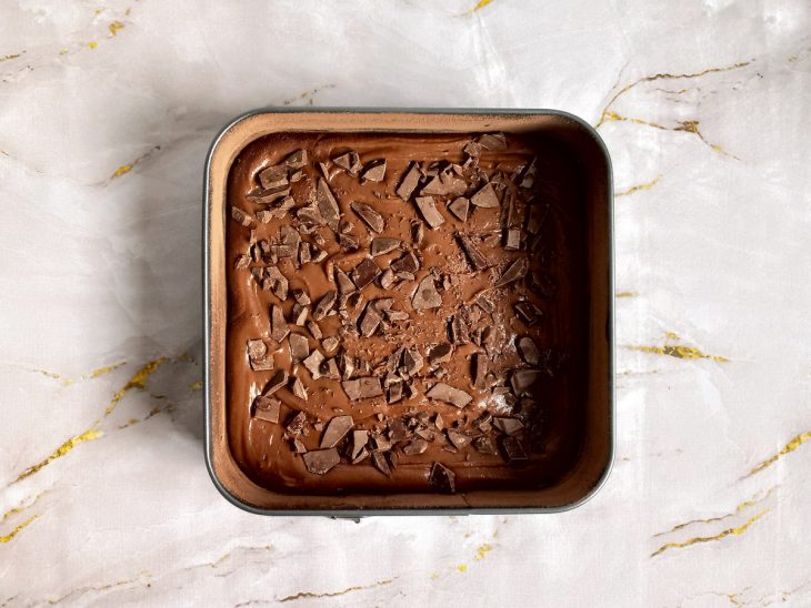 Massa de brownie e pedaços de chocolate adicionados a forma.