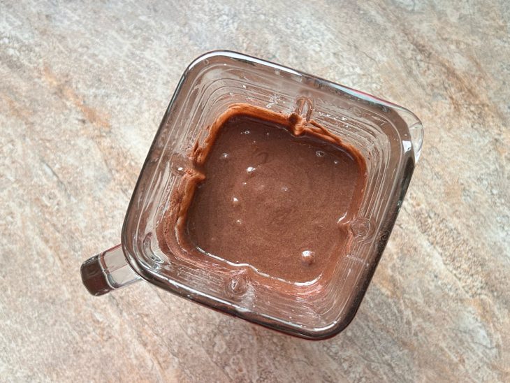 Mistura batida com Nescau adicionado no copo do liquidificador.