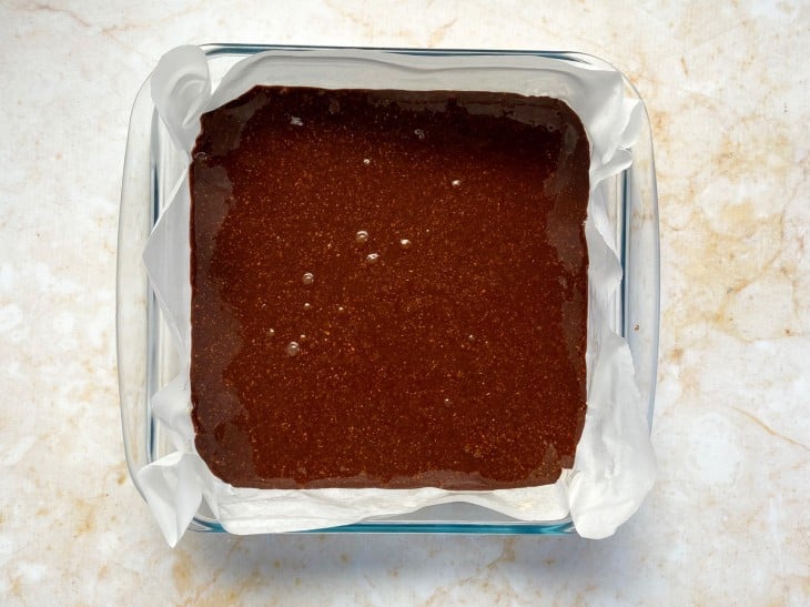 Massa do brownie despejado em uma forma com papel manteiga.