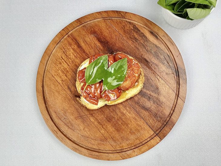 bruschetta montada com tomates assados e manjericão fresco.