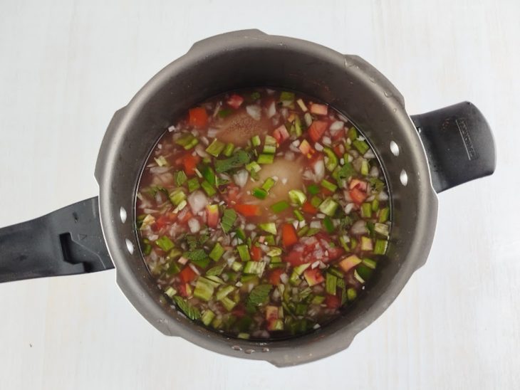 Panela grande com os buchos dispostos lado a lado e cobertos por água e temperos.