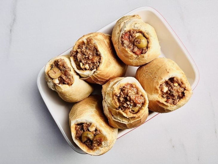 Pães franceses recheados de carne e queijo em uma travessa.