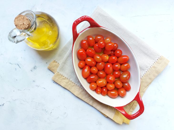 Tomate-cereja em uma travessa e azeite ao lado.