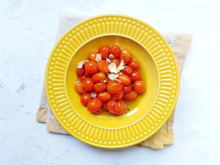 Prato fundo amarelo com tomate temperado e assado.