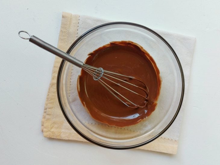 Uma tigela com chocolate derretido e um fouet.