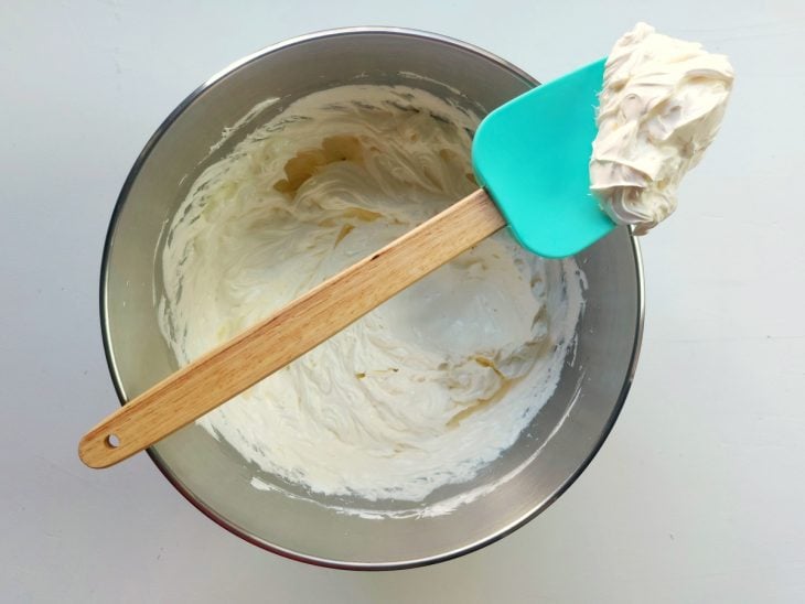 Uma espátula e uma tigela com a mistura de claras, açúcar, manteiga e baunilha.