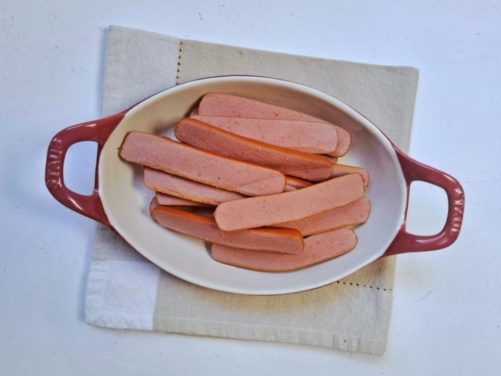 Um refratário com salsichas cozidas e cortadas ao meio.