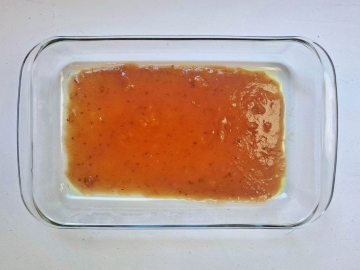 Um refratário com molho de tomate ao fundo.