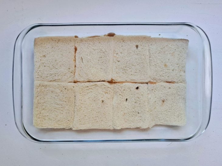 Um refratário com molho de tomate e fatias de pão.