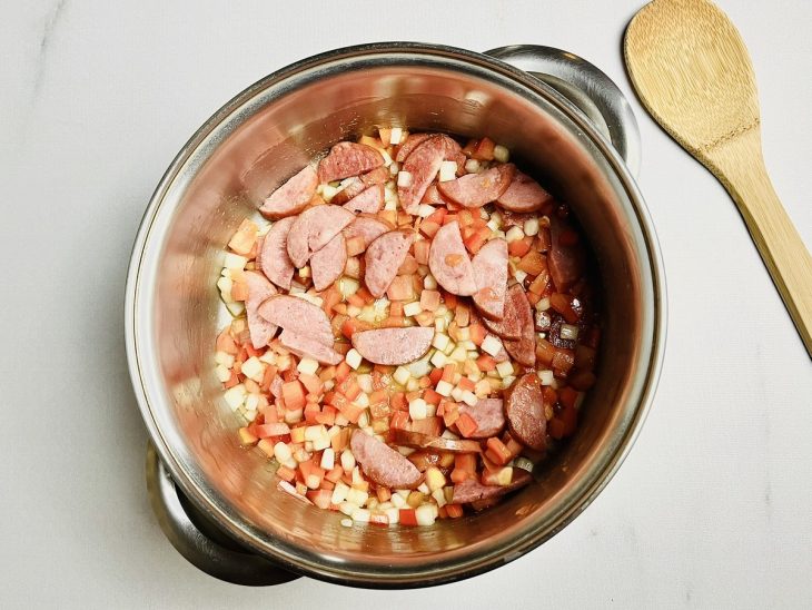 Cebola, alho, pimentões, tomates, pimenta-do-reino, orégano e sal adicionados a panela.