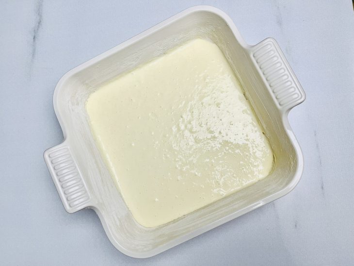 Metade da massa adicionada a uma forma untada.