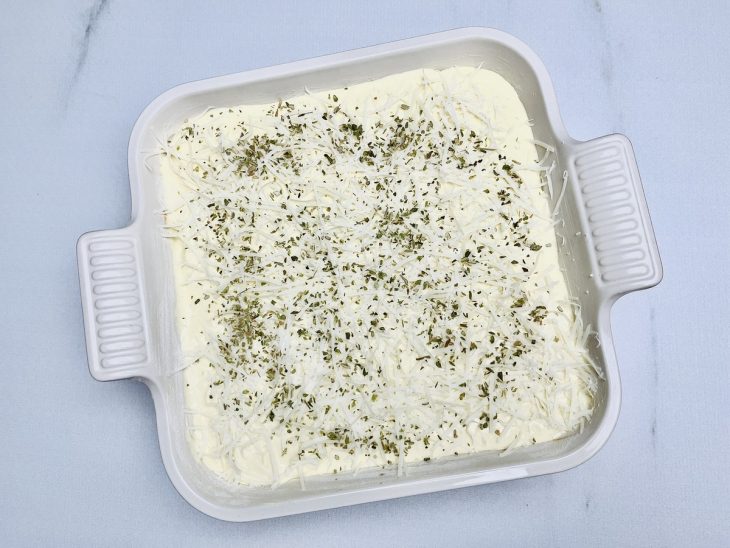 Parmesão ralado e orégano salpicados sobre a torta.