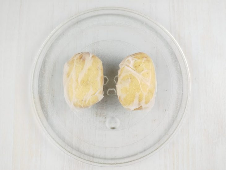 Batatas envoltas num pano acomodadas no prato do micro-ondas.