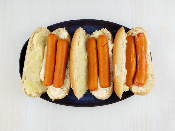 Maionese e salsichas cortadas ao meio colocadas no pão.