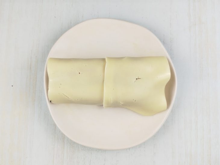 Fatias de queijo mussarela colocadas na superfície do pão.