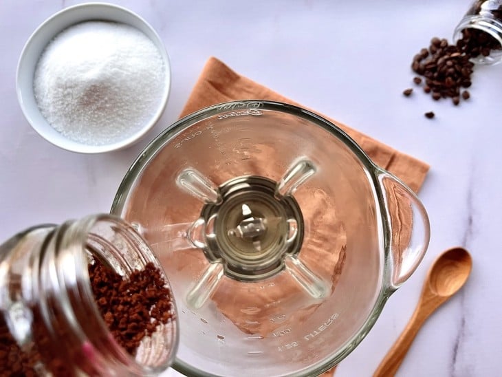 Um liquidificador com água quente, açúcar e café.