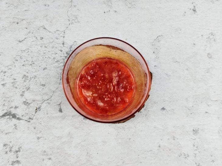 Morango macerado com açúcar em um copo.