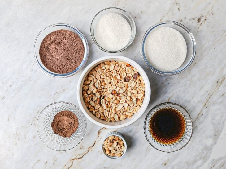 Ingredientes organizados na bancada com amendoim separado para decoração e tigela com açúcar ao lado.