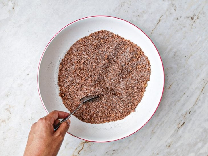 Ingredientes secos sendo adicionados ao amendoim e misturados com colher.