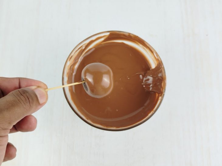 Cake pop coberto no chocolate derretido.