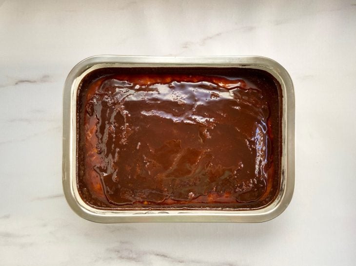Um bolo coberto com calda de chocolate durinha.