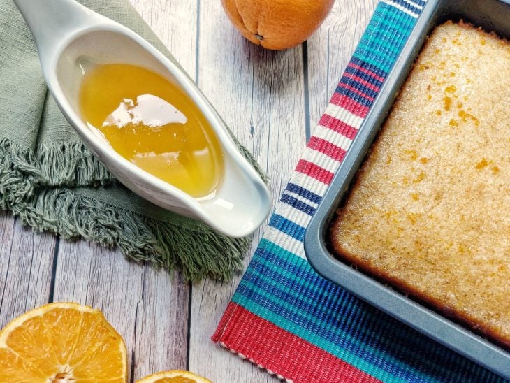 Uma forma com bolo e um recipiente com a calda de laranja.