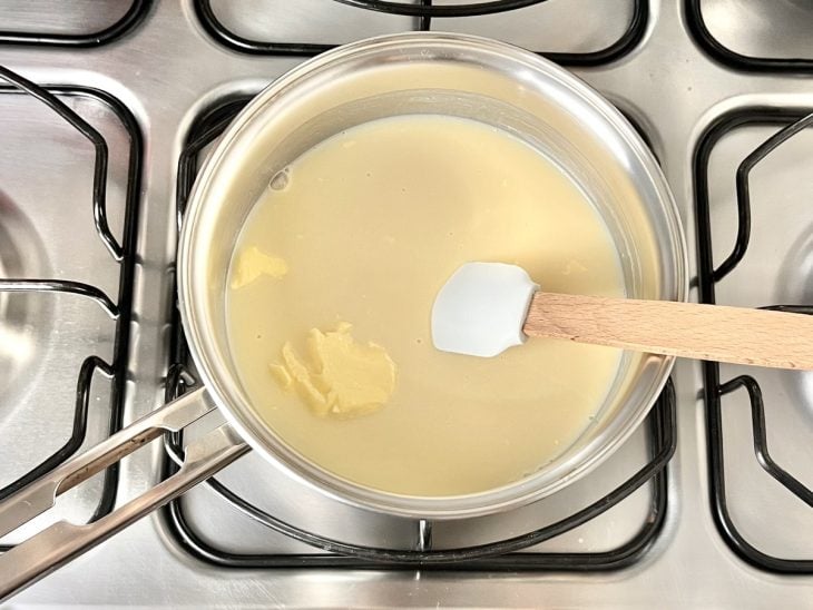 Uma panela ao fogo com leite condensado, manteiga, suco de laranja e sal.
