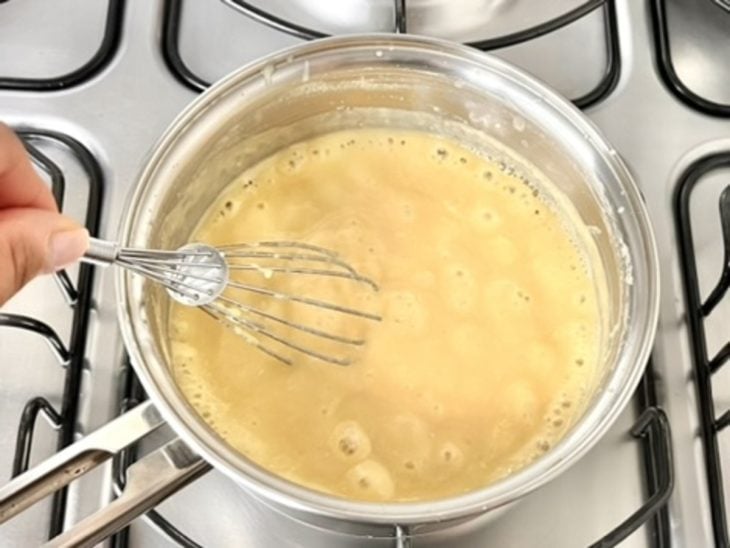 Uma panela ao fogo com a mistura dos ingredientes fervendo.