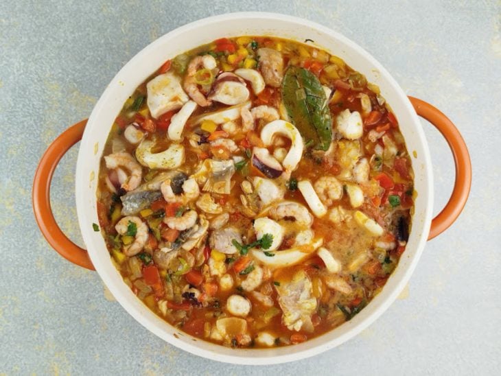 Caldo de camarão, molho de tomate e azeite de dendê sendo incorporados.