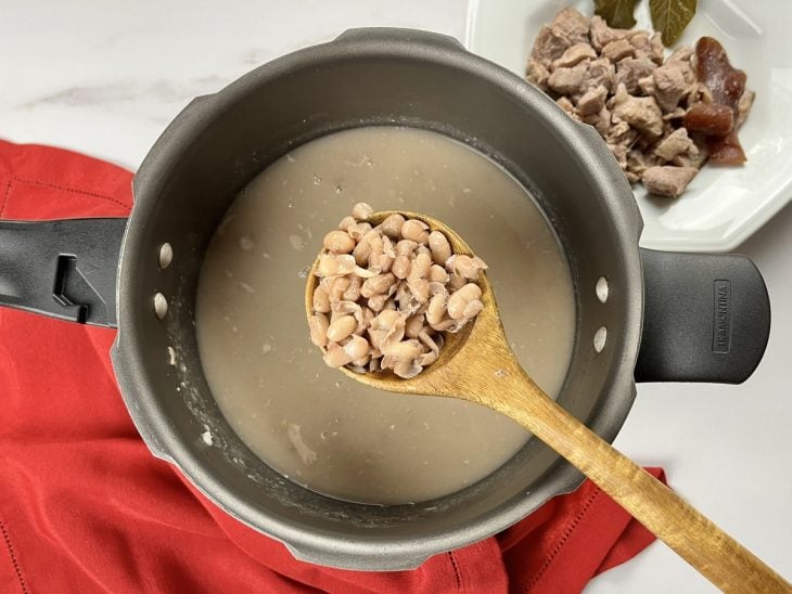 Uma panela de pressão com o feijão e a carne cozidos.
