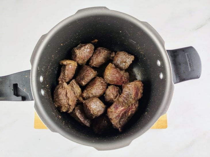 Pedaços de costela dourados na panela de pressão.