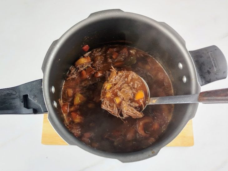 Carne desfiada, polpa de tomate, vinho e tomate adicionados na panela de pressão.
