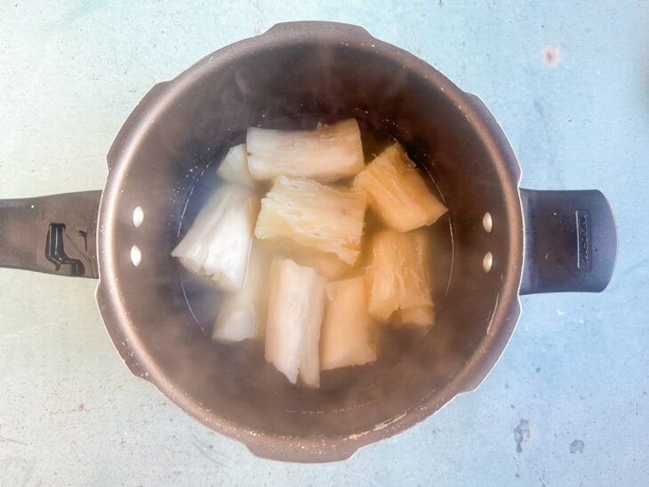 Aipim sendo cozido em uma panela com bastante água até ficar bem macio.